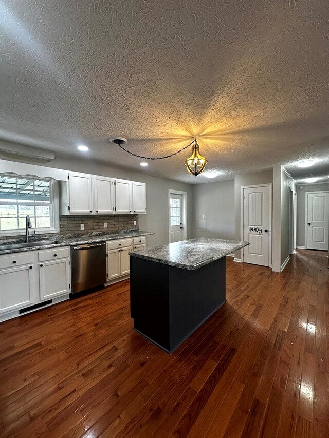 kitchen featuring dishwasher, a kitchen island, dark wood-type flooring, white cabinetry, and a sink