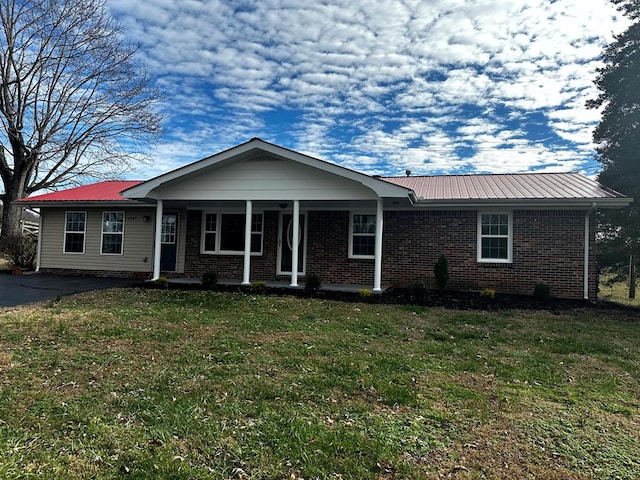 ranch-style home with a front yard, metal roof, and brick siding