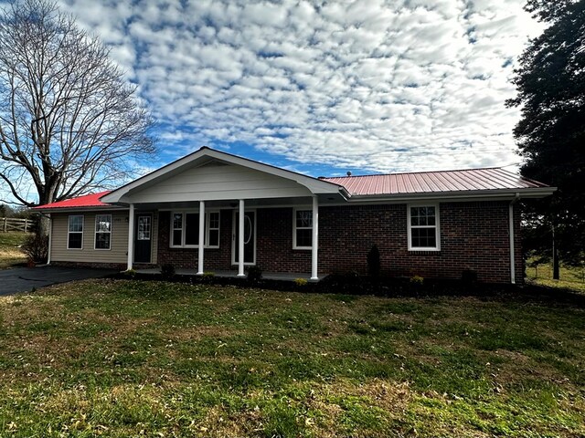 single story home with metal roof, brick siding, a front lawn, and a porch