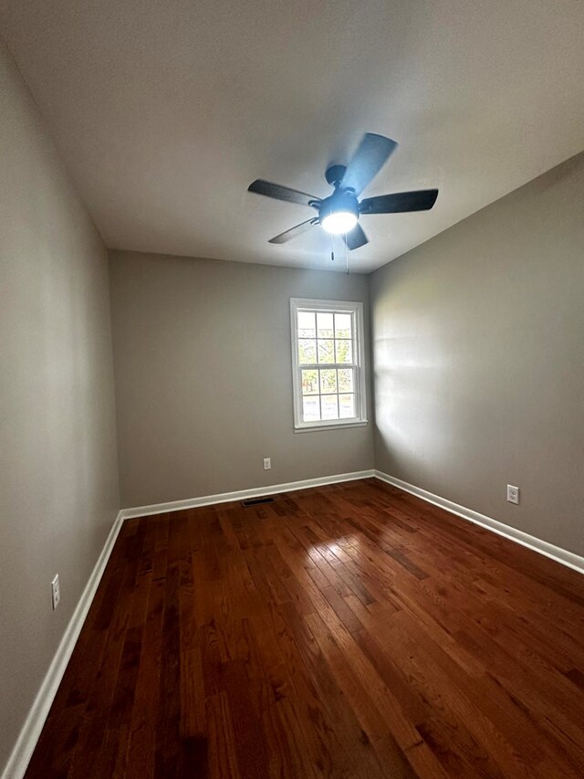 spare room featuring dark wood-style flooring, visible vents, ceiling fan, and baseboards