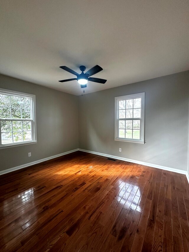 unfurnished room with dark wood-style floors, baseboards, and a wealth of natural light