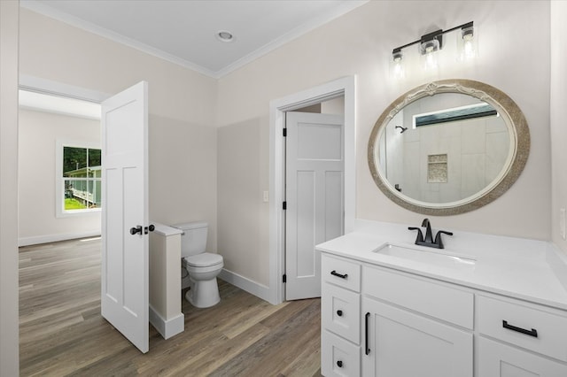 bathroom with baseboards, toilet, wood finished floors, crown molding, and vanity