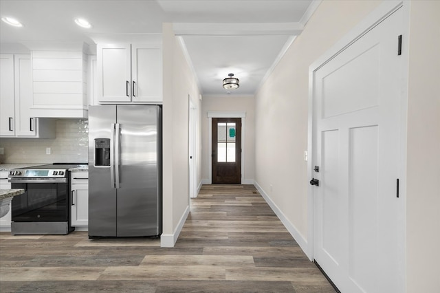 kitchen featuring crown molding, tasteful backsplash, appliances with stainless steel finishes, white cabinetry, and wood finished floors