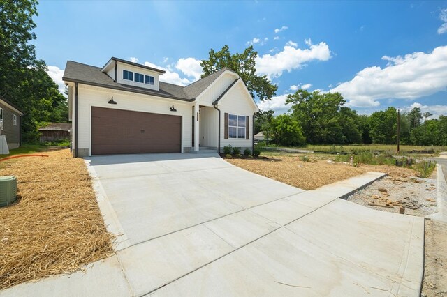 view of front of property with an attached garage, central air condition unit, and concrete driveway