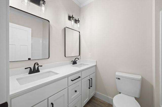 full bathroom featuring double vanity, a sink, toilet, and baseboards