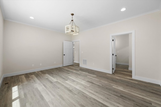 empty room featuring recessed lighting, light wood-style flooring, an inviting chandelier, ornamental molding, and baseboards