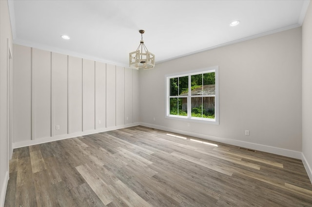 unfurnished room with a notable chandelier, wood finished floors, visible vents, baseboards, and crown molding