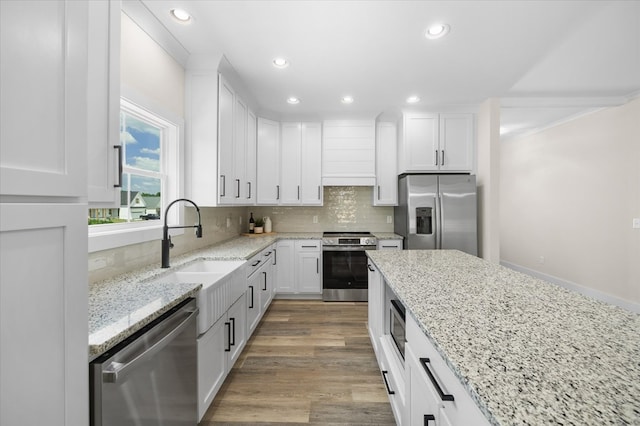 kitchen featuring appliances with stainless steel finishes, tasteful backsplash, white cabinets, and light stone countertops