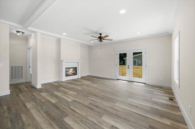 unfurnished living room with baseboards, visible vents, a glass covered fireplace, wood finished floors, and french doors