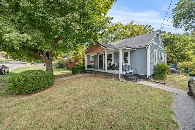 bungalow-style house featuring covered porch, metal roof, and a front lawn