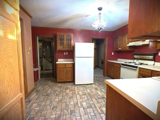 kitchen with glass insert cabinets, light countertops, pendant lighting, and white appliances