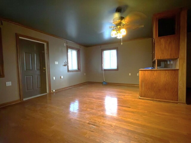 unfurnished living room with light wood-style floors, ceiling fan, and baseboards