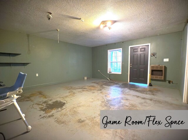 foyer entrance featuring a textured ceiling, unfinished concrete flooring, and heating unit