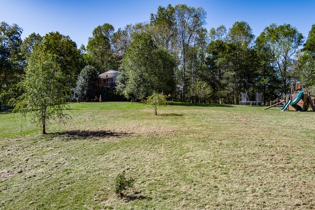 view of yard with a trampoline and a playground