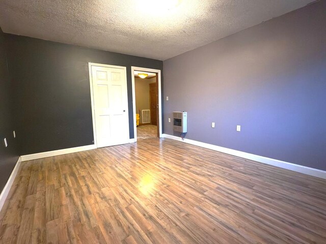 empty room featuring a textured ceiling, baseboards, and wood finished floors