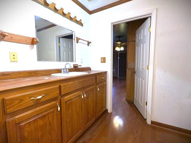 bathroom with ornamental molding, vanity, baseboards, and wood finished floors