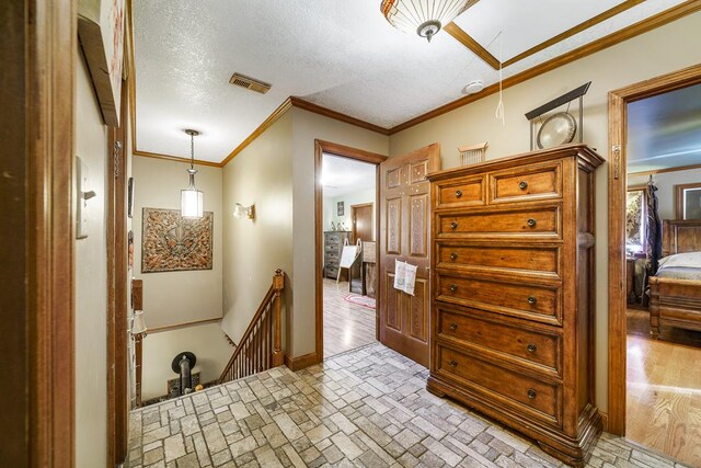 corridor featuring brick floor, visible vents, ornamental molding, and an upstairs landing