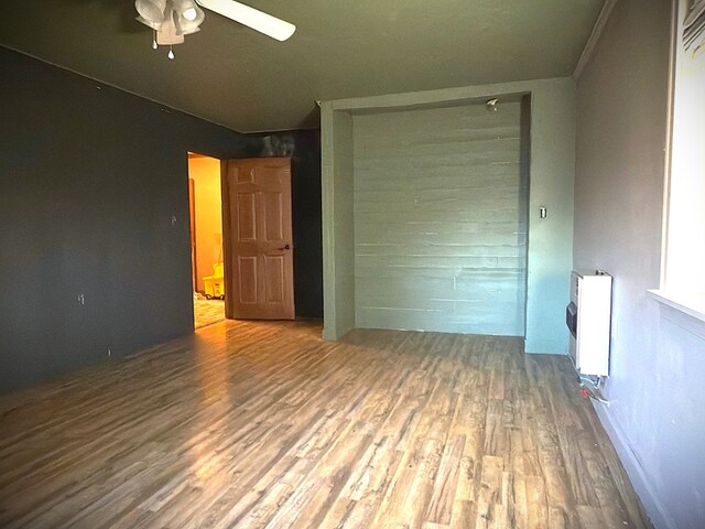 interior space with a ceiling fan, heating unit, and wood finished floors