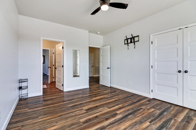 unfurnished bedroom featuring dark wood-style floors, ceiling fan, baseboards, and a closet