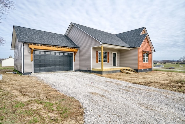 view of front facade with a garage, driveway, roof with shingles, and covered porch