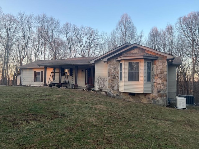 view of front facade featuring a porch, a front yard, and cooling unit