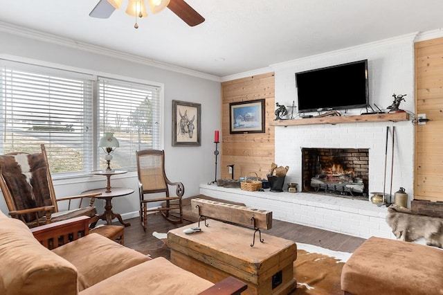 living room featuring dark wood-type flooring, a ceiling fan, baseboards, a brick fireplace, and crown molding