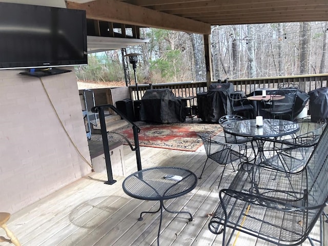 wooden terrace with a grill and outdoor dining space