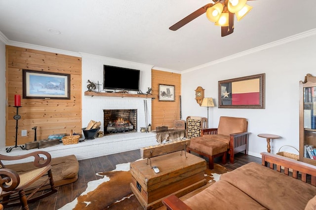 living area featuring dark wood-type flooring, a fireplace, a ceiling fan, baseboards, and ornamental molding