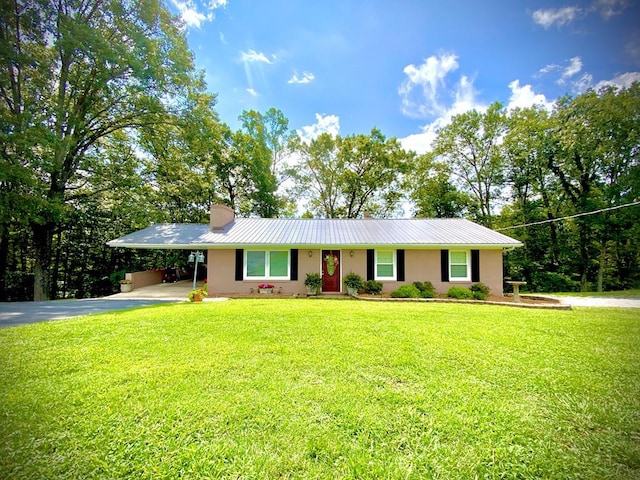 ranch-style home with metal roof, an attached carport, driveway, a chimney, and a front yard