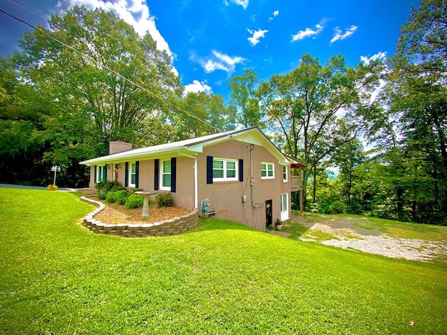 view of property exterior featuring driveway, a yard, a chimney, and brick siding