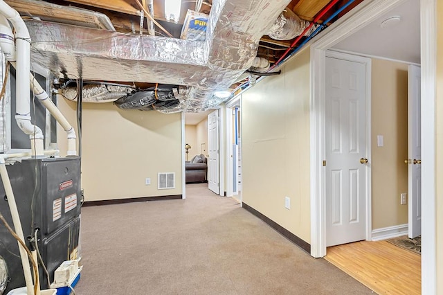 unfinished below grade area with carpet, visible vents, and baseboards