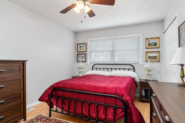 bedroom featuring light wood-type flooring, visible vents, ceiling fan, and baseboards