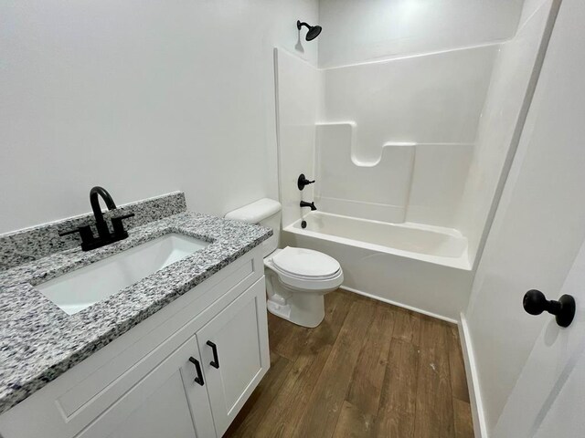 full bath with toilet, washtub / shower combination, wood finished floors, and vanity