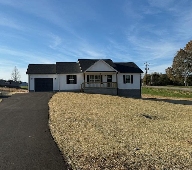 view of front of house featuring aphalt driveway, a porch, and a garage