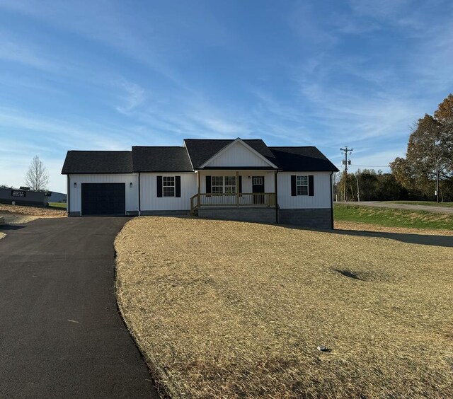 view of front of home featuring a front yard, covered porch, driveway, and an attached garage