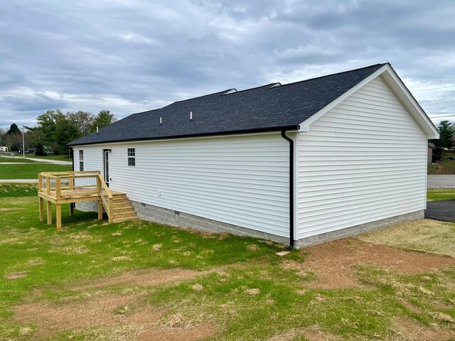 view of side of home with a yard and roof with shingles