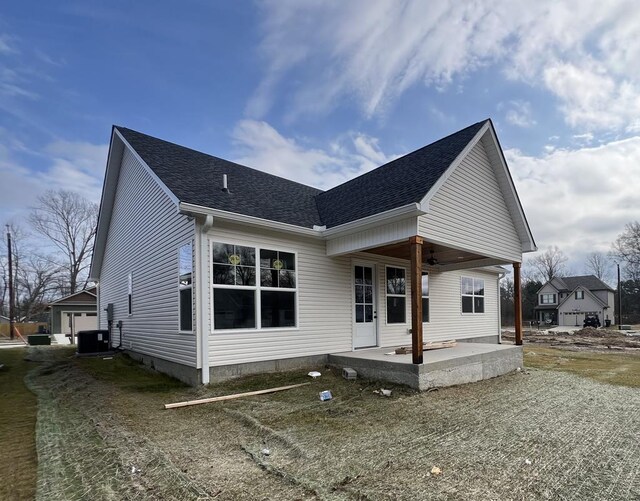 back of property featuring a shingled roof, central AC, and a patio