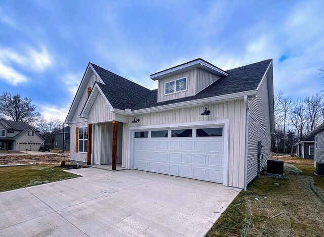 view of front of house featuring a garage, roof with shingles, driveway, and central air condition unit