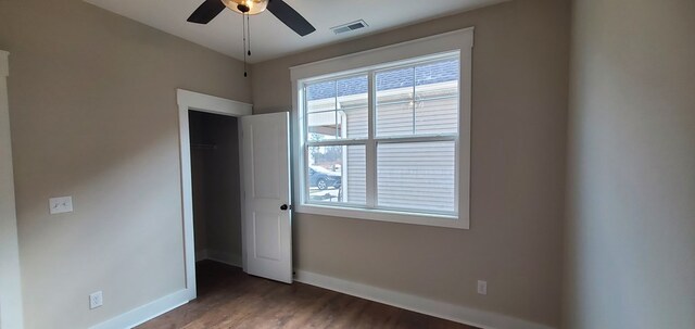 empty room with dark wood-style floors, visible vents, baseboards, and a ceiling fan