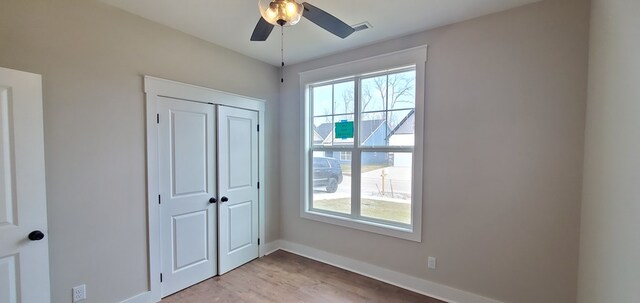 unfurnished bedroom with visible vents, light wood finished floors, baseboards, and multiple windows