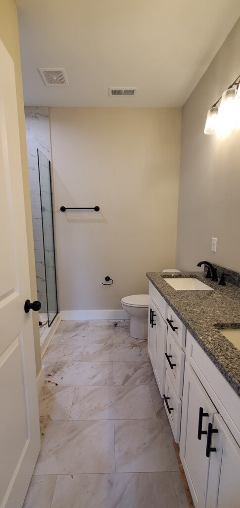 bathroom featuring toilet, a stall shower, a sink, and visible vents