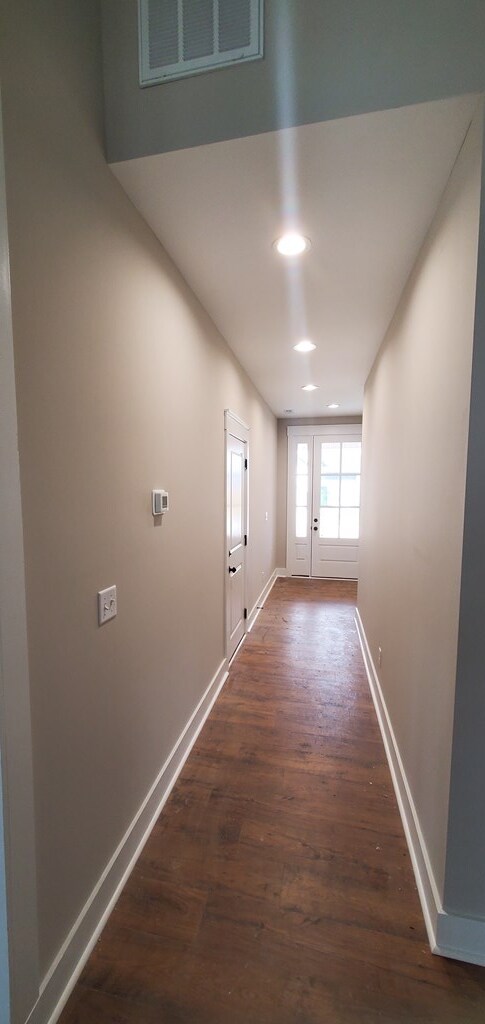 hall with baseboards, visible vents, dark wood-type flooring, and recessed lighting