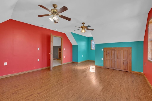 additional living space featuring lofted ceiling, ceiling fan, light wood-style flooring, and baseboards