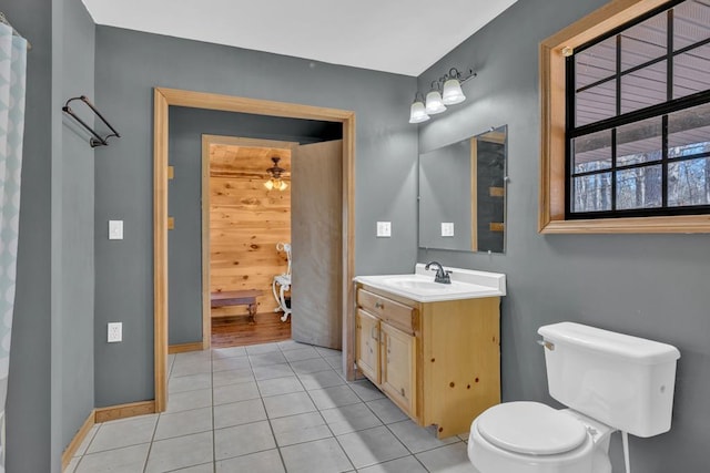 bathroom with baseboards, toilet, ceiling fan, tile patterned floors, and vanity