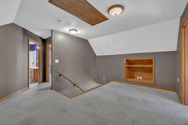 bonus room featuring light carpet, attic access, baseboards, lofted ceiling, and built in shelves