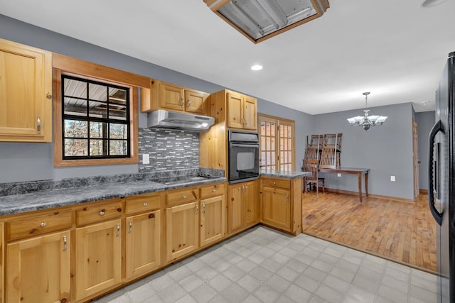 kitchen with a wealth of natural light, decorative light fixtures, under cabinet range hood, and black appliances