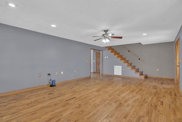 unfurnished living room with light wood-type flooring, visible vents, stairway, and baseboards