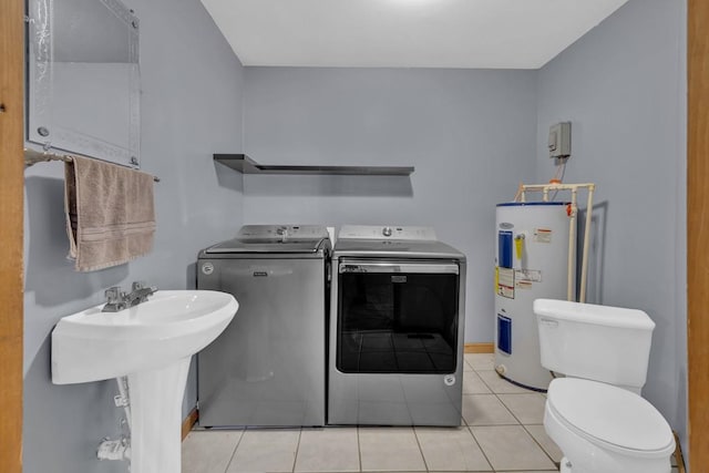 washroom featuring laundry area, light tile patterned floors, washer and clothes dryer, water heater, and a sink