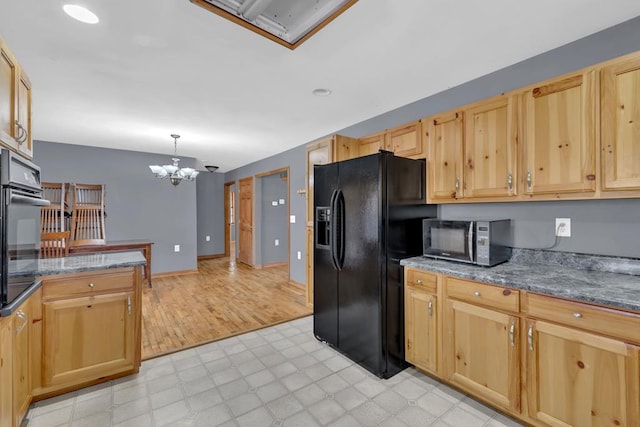 kitchen with dark stone counters, light floors, black appliances, light brown cabinets, and pendant lighting