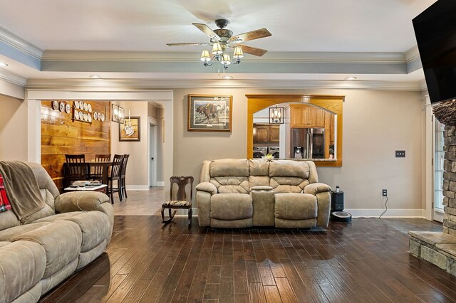 living room with a tray ceiling, dark wood-style flooring, and baseboards